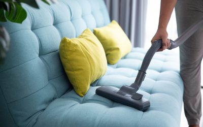 close up of man's hand cleaning couch using vacuum cleaner at home